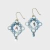 Boucles d’oreilles pendantes en acier inoxydable plaqué or, réalisées à la main selon la technique de la frivolité.fils dégradés de bleu allant du ciel azur au bleu marine, est sublimé par de petites perles assemblées à la main