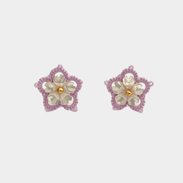 Boucles d'oreilles artisanales en forme de fleur, fabriquées à la main selon la technique de la frivolité, associant fil polyester mauve et véritable nacre blanche façonnée en pétale, incarnant élégance et raffinement.